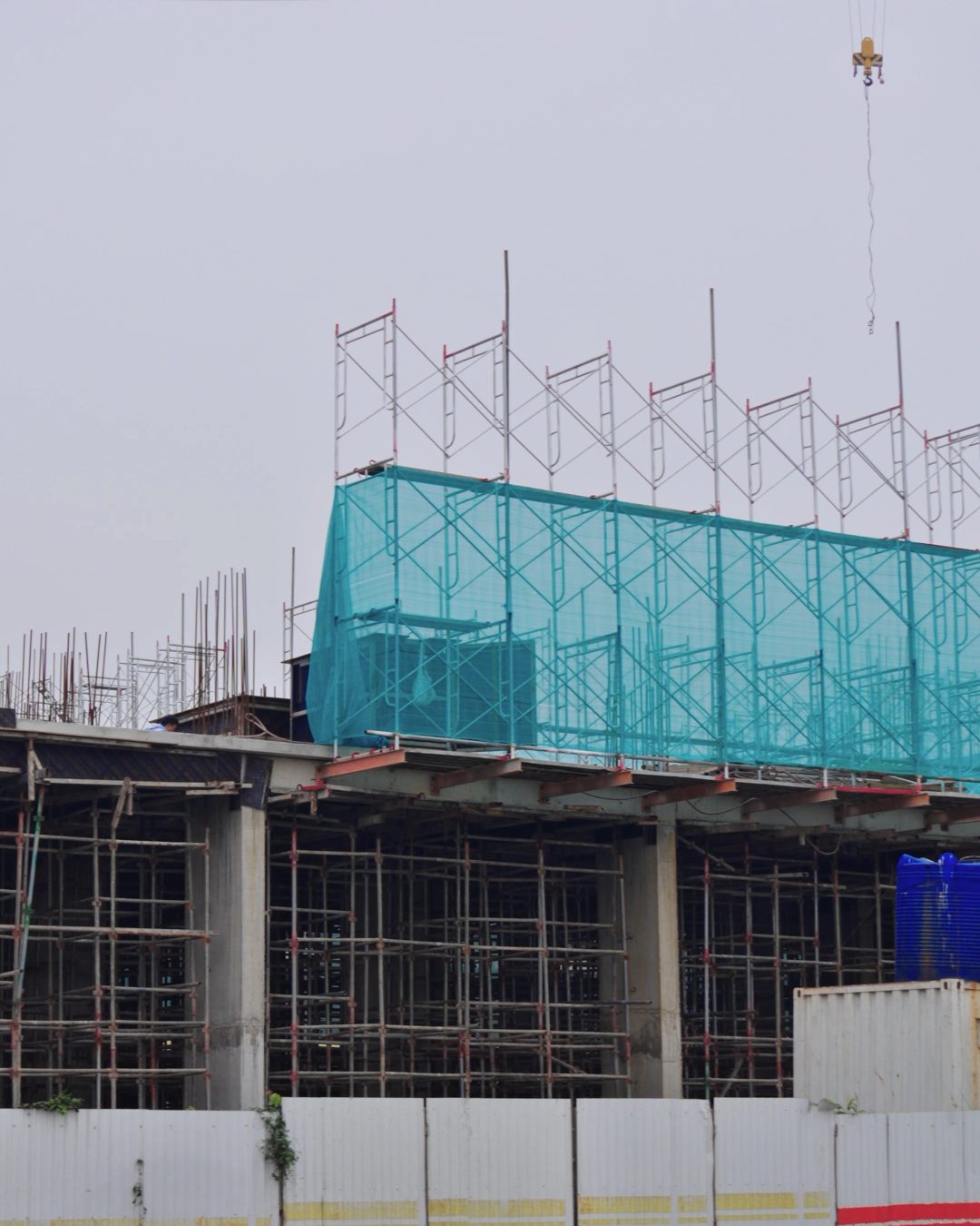 Ảnh thực tế công trường Happy Home Thanh Hóa tháng 06/2026 — phần khối đế và kết cấu tòa đang thi công với giàn giáo, lưới bao che